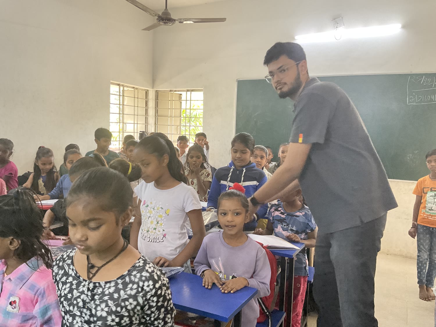 A volunteer distributing school kits to children in a classroom